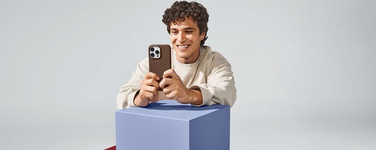 man smiling and holding iphone 16 in a brown OtterBox cactus leather phone case